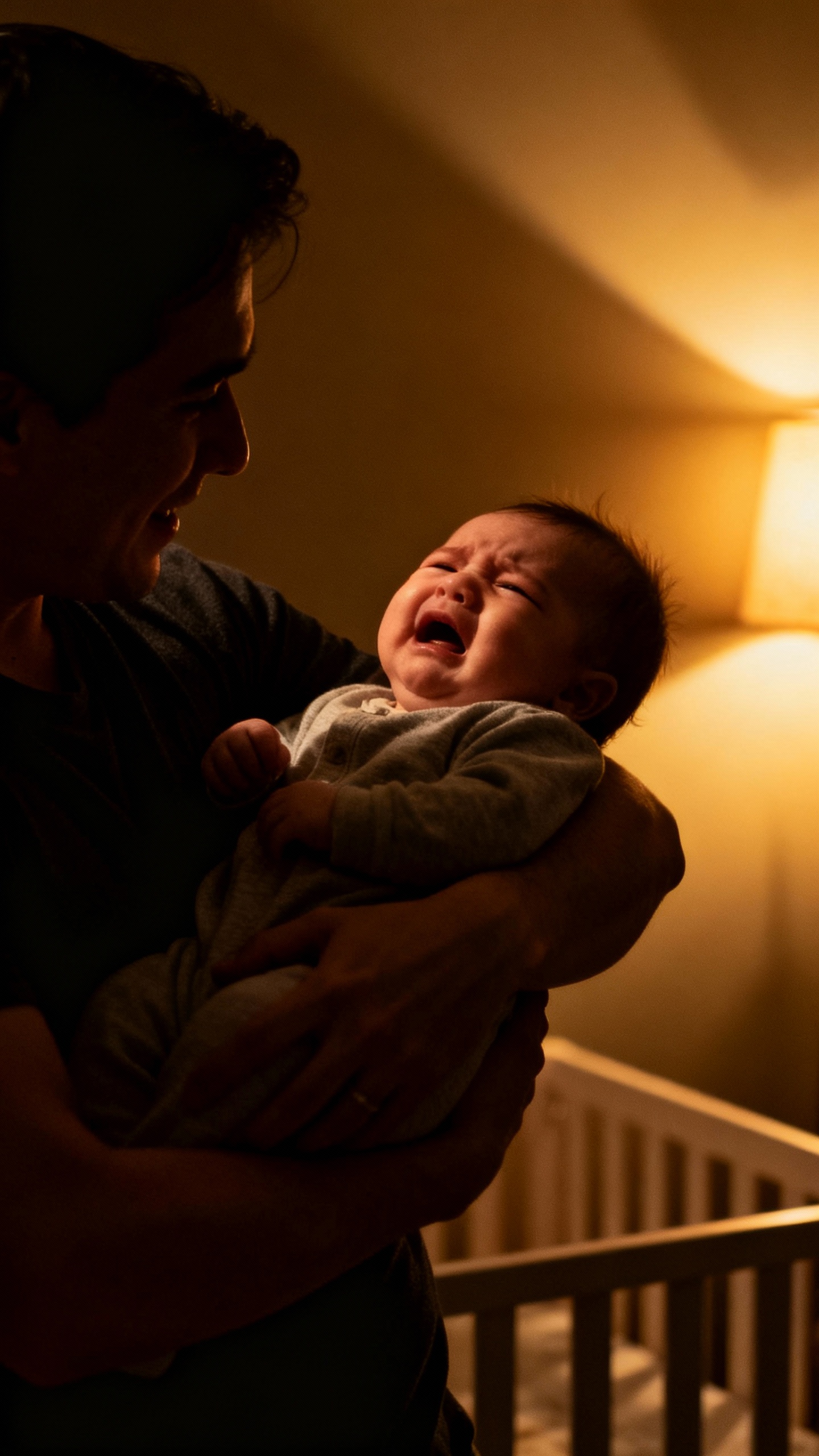 Parent rocking fussy infant, dim nursery, warm lamplight