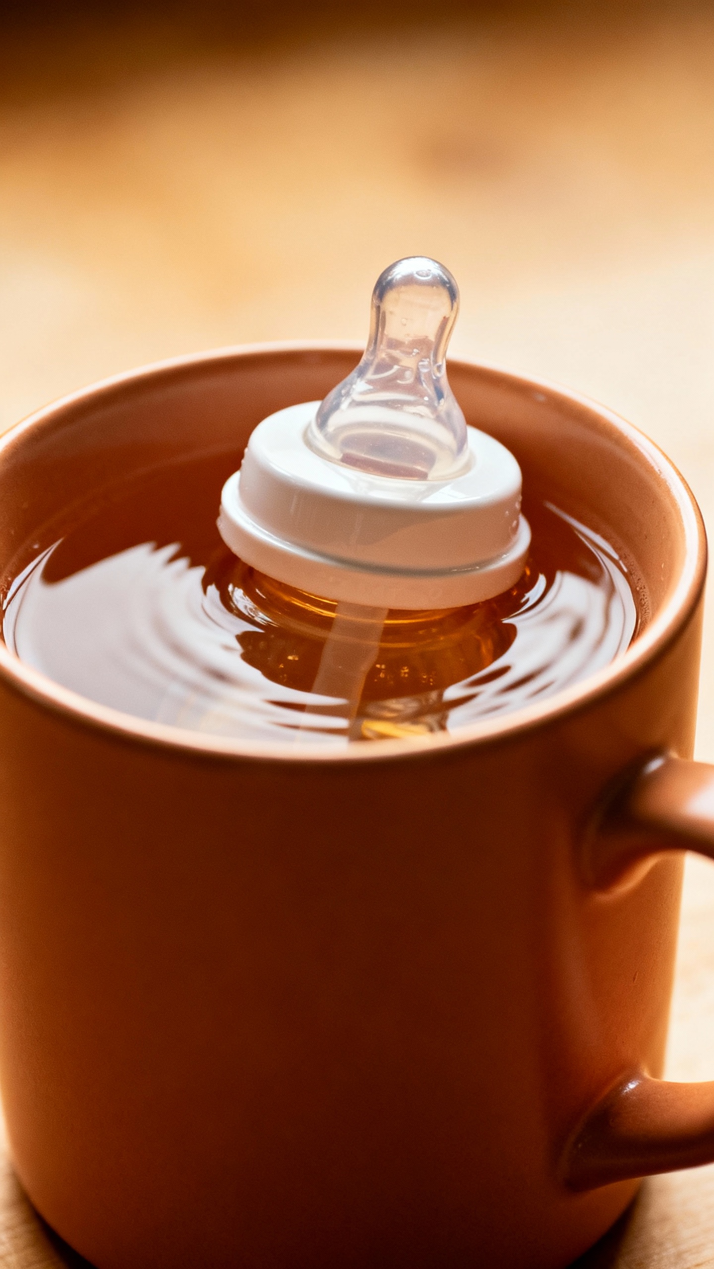 baby bottle in ceramic mug of warm water