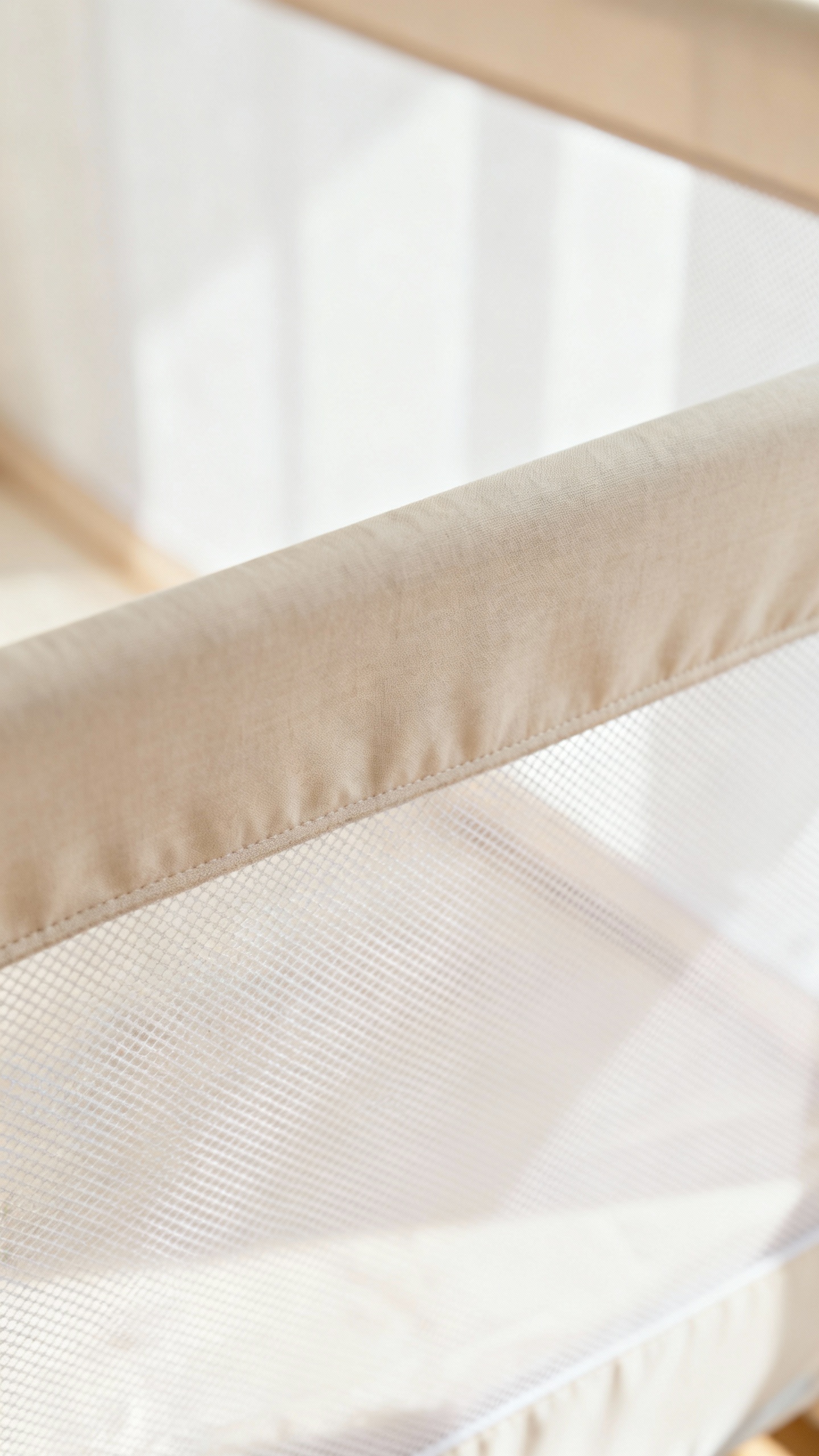 Washable mesh bassinet walls close-up, soft neutral nursery backdrop